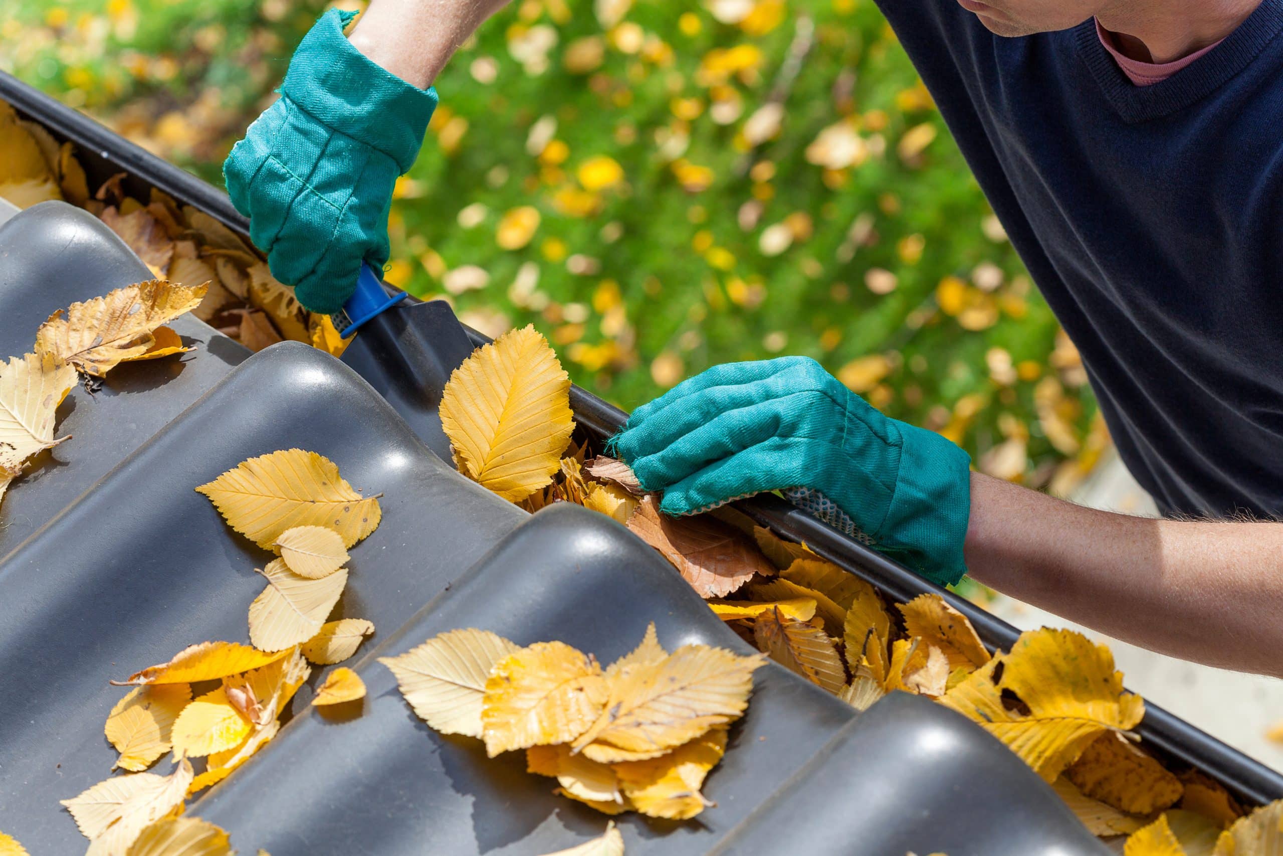 Anställd hos Fastighetstillsyn tar hand om en kunds hem och rensar löv i trädgården.